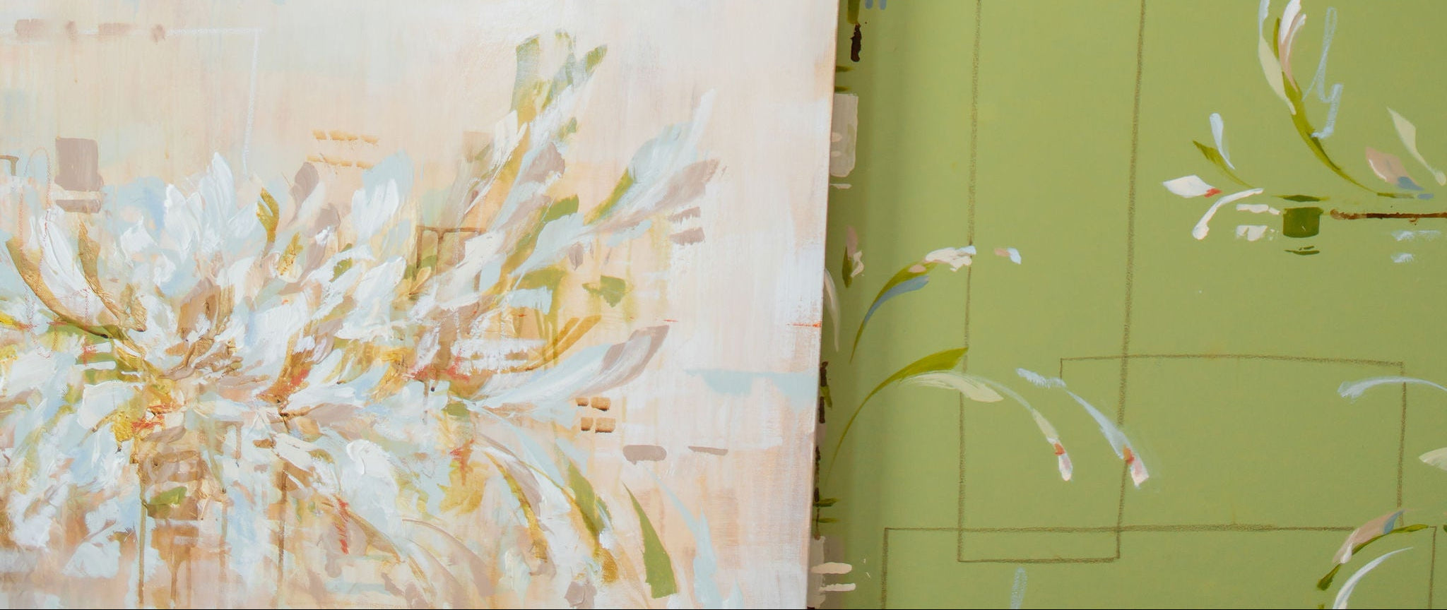 A woman in a white sleeveless dress with intricate beaded shoulder straps stands behind a large green canvas featuring white floral brushstrokes, holding a smaller floral canvas in front of a warm beige studio backdrop.